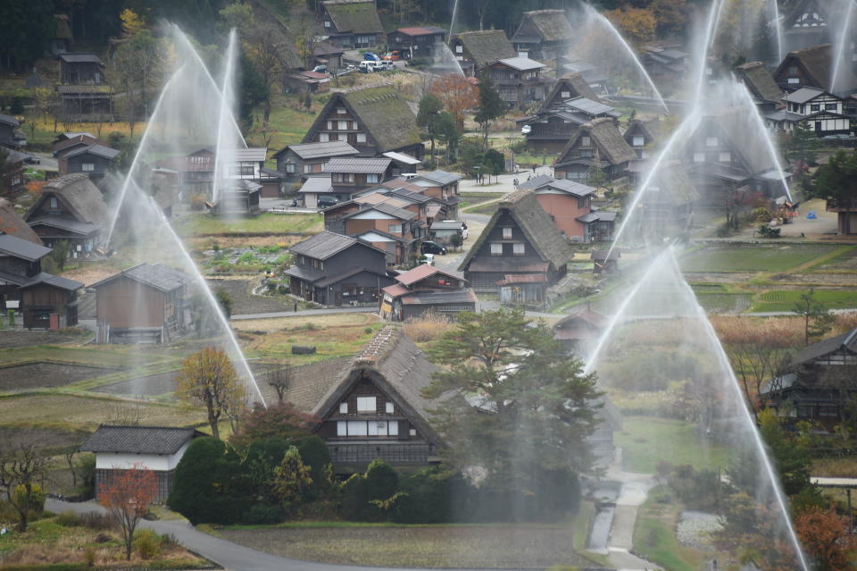 SHIRAKAWA, JAPAN - NOVEMBER 09:The frond house is Wada House, the biggest house at Shirakawa-go.   Water is seen discharged over the traditional farm houses at Shirakawa-go, the UNESCO World Heritage site on November 9, 2014 in Shirakawa, Japan. This annual drill is held to prevent fire.  (Photo by Kaz Photography/Getty Images)