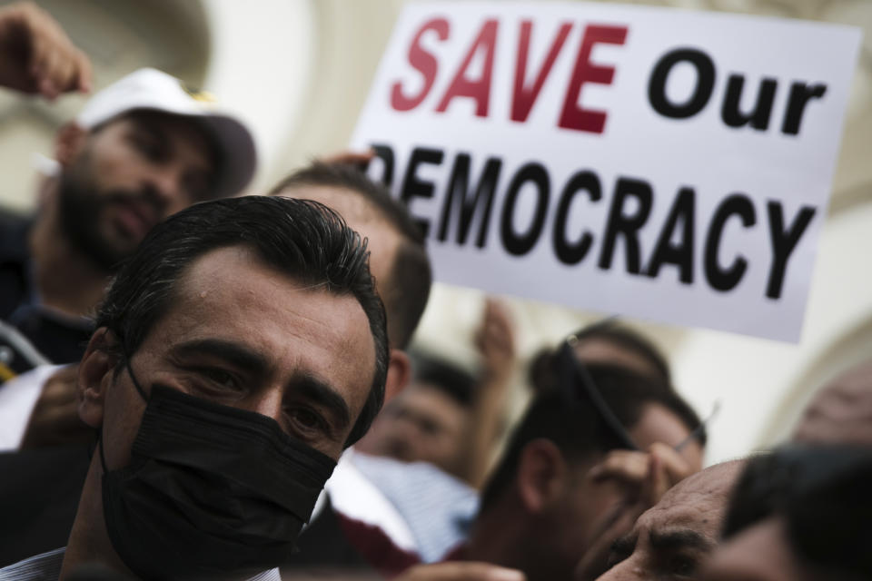 Tunisian constitutional law professor Jaouhar Ben Mbarek, left, attends a protest against Tunisian President Kais Saied, Saturday, Sept. 18, 2021 in Tunis. In July Tunisian President Kais Saied fired the country's prime minister and froze parliament's activities after violent demonstrations over the country's pandemic and economic situation. The movement made by Saied was considered by his opponents as a coup. (AP Photo/Riadh Dridi)