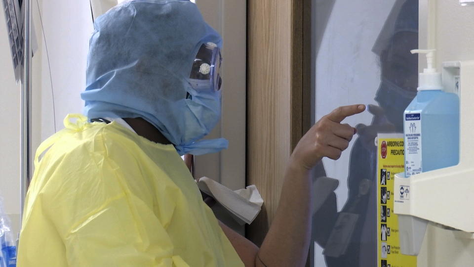 Nurse Hailey Tucker, points out supplies to Dr. Ismael Yussuf, who is dressed in full suit of PPE and making his daily rounds to check on COVID-19 patients inside isolated ICU rooms at Fort Washington Medical Center on Thursday, June 18, 2020, in Fort Washington, Md. Clinical staff on the frontlines say the coronavirus pandemic is far from over and are urging the public to still follow safety precautions to limit the spread of the disease. (AP Photo/Nathan Ellgren)