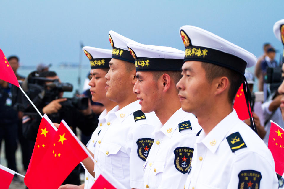 Chinese navy soldiers with small flags seen at Asean fleet parade in Pattaya. Soldiers are passing Beach Road. In background are many photographers and press.