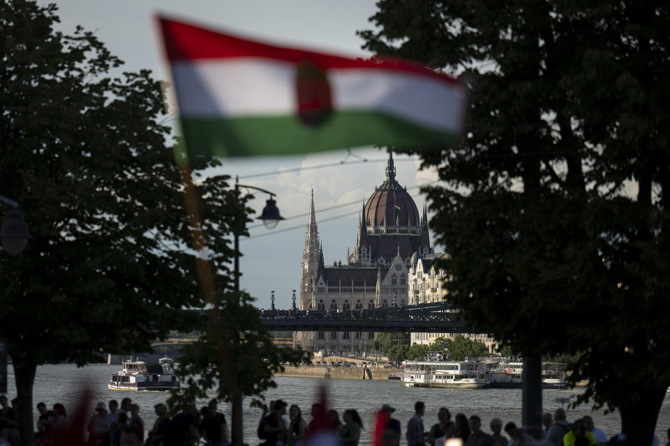 People wave a Hungarian national flag next to the Danube river, in Budapest, Thursday May 30, 2024, where politicians took to the debate stage ahead of the European Parliament elections. The debate, where the leaders of 11 party lists running in the June 9 elections, is the first to be broadcast by Hungary's public media since 2006, while protesters outside demonstrated against the public broadcaster that is hosting the event. (AP Photo/Denes Erdos)