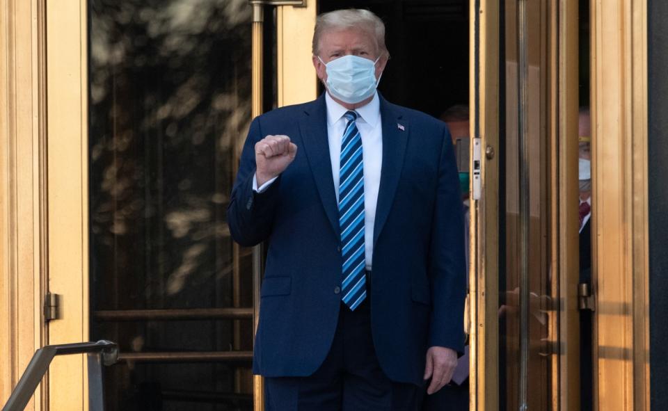 Trump holds up a clenched fist as he exits the hospital.