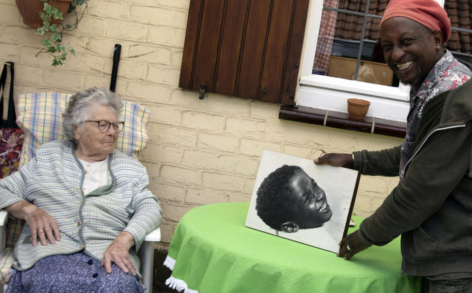 In this photo taken on Monday, June 22, 2020, Eric Baranyanka, right, and his foster mother Emma Monsaert look at a photo of Eric as a young boy in Lembeek, Belgium. Baranyanka fled political persecution in the Belgian protectorate of Burundi in the 1960's, landing half a world away at a military airport in Brussels, before being fostered by Emma Monsaert and her husband Paul. (AP Photo/Virginia Mayo)