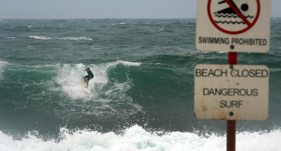 A surfer taking on a large wave on a closed beach