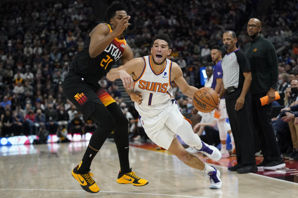 Phoenix Suns guard Devin Booker (1) drives around Utah Jazz center Hassan Whiteside (21) in the second half during an NBA basketball game Wednesday, Jan. 26, 2022, in Salt Lake City. (AP Photo/Rick Bowmer)