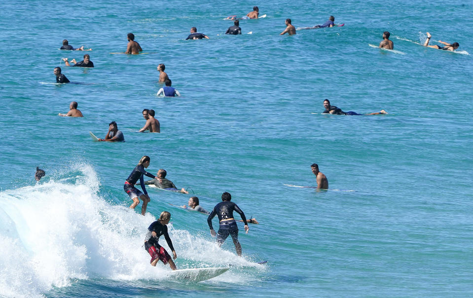 People are seen swimming and surfing at the beach.