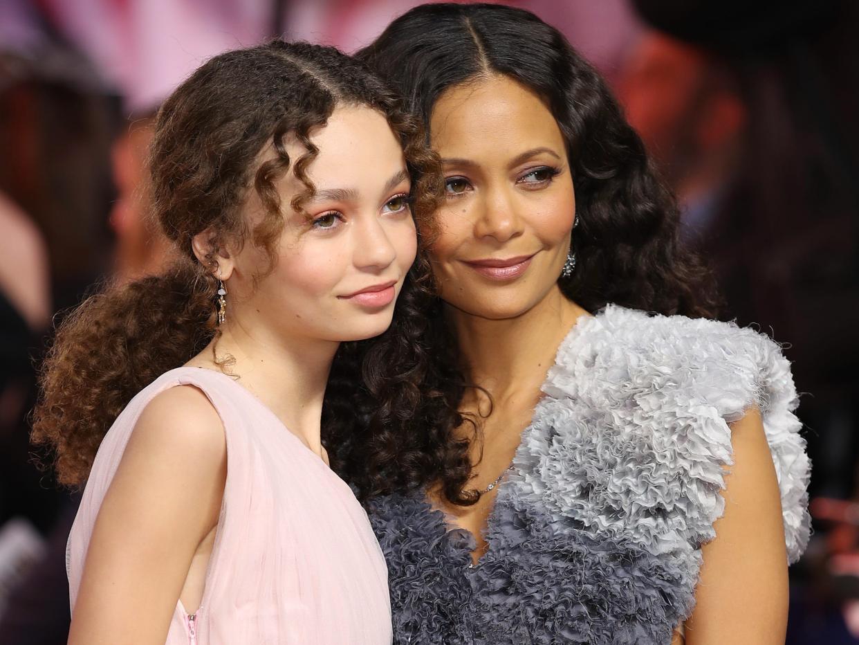 A young girl and her mother pose together on the red carpet.