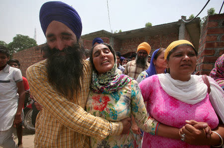 Relatives console the wife (C) of Paramjit Singh, an Indian army soldier who the Indian army says was killed by Pakistani soldiers while patrolling the de facto border in the disputed Kashmir region on Monday, as her husband's body is taken away for cremation in the village of Vein Poin on the outskirts of Amritsar, India May 2, 2017. REUTERS/Munish Sharma