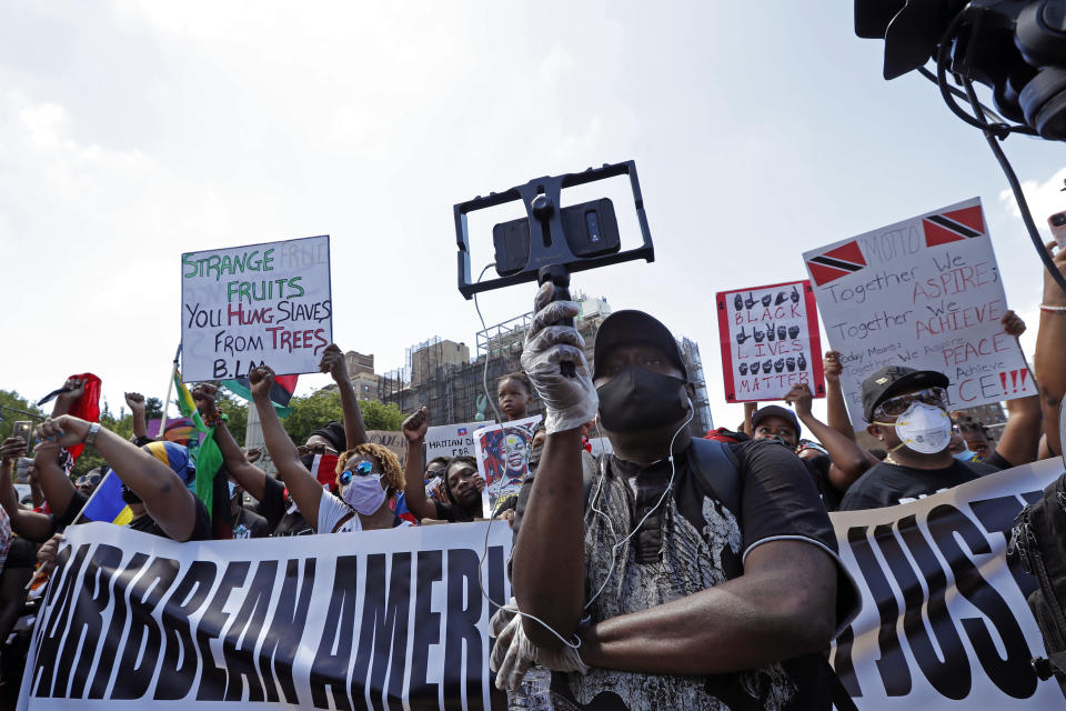 A man uses a bracket to hold his cell phone camera as he records speakers during a Caribbean-led Black Lives Matter rally at Brooklyn's Grand Army Plaza, Sunday, June 14, 2020, in New York. (AP Photo/Kathy Willens)