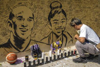 A basketball fan lights a candle next to a mural of former NBA star Kobe Bryant and his daughter Gianna outside the "House of Kobe" basketball court in Valenzuela, Metro Manila, Philippines. (Credit: Ezra Acayan/Getty Images)