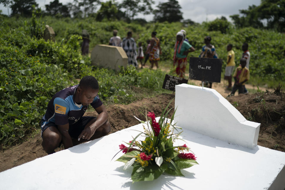 A man prays over the grave of a relative after painting the gravestone white, as a symbol that the soul of the deceased remains in peace, as members of the family stand by, during the Day of the Dead celebrations in Abidjan, Ivory Coast, Monday, Nov. 2, 2020. (AP Photo/Leo Correa)