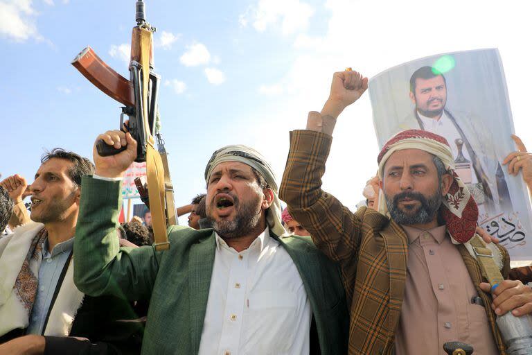 Hombres yemeníes blanden sus armas y sostienen retratos del líder hutí Abdul Malik al-Houthi durante una protesta en solidaridad con el pueblo palestino en Saná, la capital yemení controlada por los hutíes, el 5 de enero de 2024. (MOHAMMED HUWAIS / AFP)