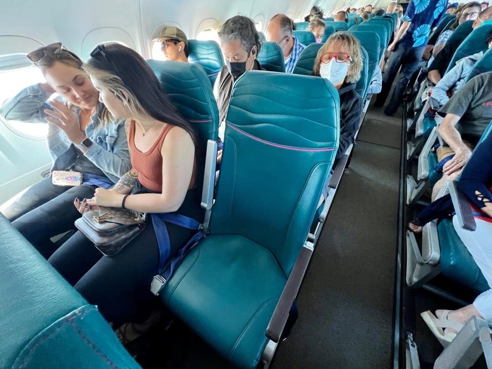 Empty plane seat surrounded by seated passengers on Hawaiian Airlines flight