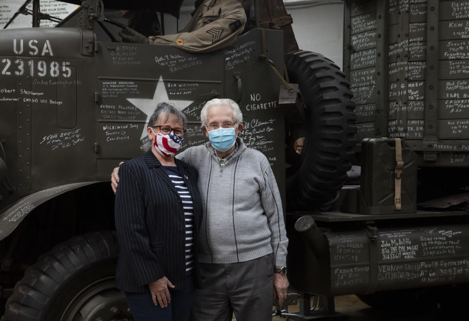 In this photo taken on Tuesday, May 5, 2020, directors of the Remember Museum 39-45, Marcel Schmetz, right, and Mathilde Schmetz pose in front of a World War II vintage truck with their mouth masks on in Thimister-Clermont, Belgium. The couple run a war museum, right where the Battle of the Bulge, Hitler's last stand to change the tide of the war, took place. But what was supposed to be the highlight of the year is now spent in isolation with Mathilde behind closed doors of the museum. (AP Photo/Virginia Mayo)