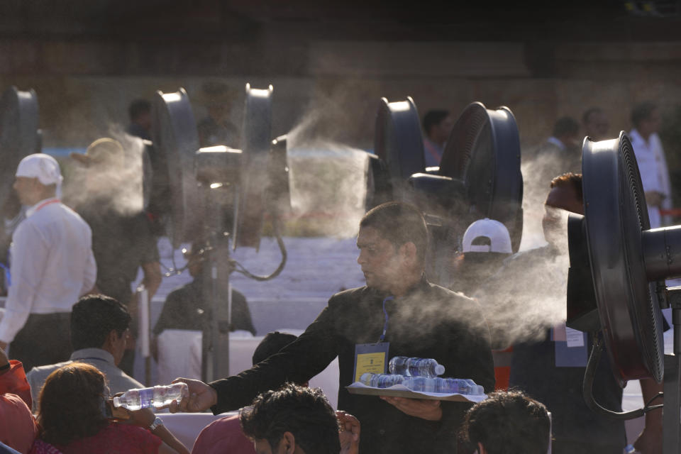 FILE- A worker distributes water bottles to guests sitting near water coolers to ward off the heat at the swearing-in-ceremony of Narendra Modi as Indian prime minister at the Indian presidential palace in New Delhi, India, Sunday, June 9, 2024. A monthslong heatwave across swathes of India has killed more than 100 people and led to over 40,000 suspected cases of heat stroke in the last three and a half months, a Health Ministry official said Thursday, June 20. (AP Photo/Manish Swarup, File)