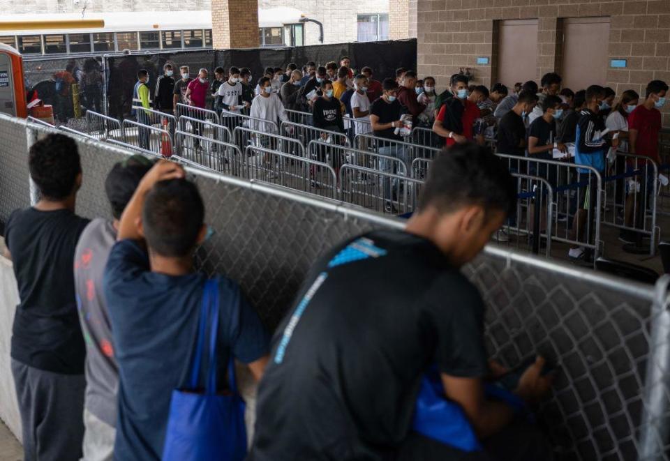 Migrants look over a fence as they try to locate family members and friends that arrived at a processing center in Brownsville, Texas, on May 11, 2023. The US on May 11, 2023, will officially end its 40-month Covid-19 emergency, also discarding the Title 42 law, a tool that has been used to prevent millions of migrants from entering the country. / Credit: ANDREW CABALLERO-REYNOLDS/AFP via Getty Images