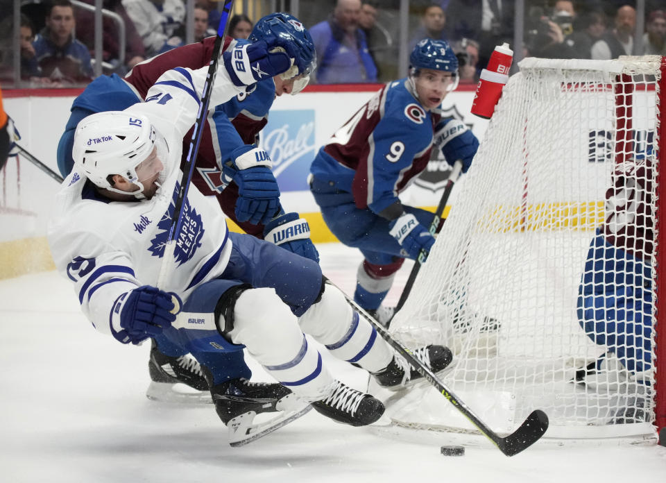 Toronto Maple Leafs center Alexander Kerfoot tumbles to the ice while fighting for control of the puck against Colorado Avalanche defenseman Erik Johnson during the second period of an NHL hockey game Saturday, Dec. 31, 2022, in Denver. (AP Photo/David Zalubowski)