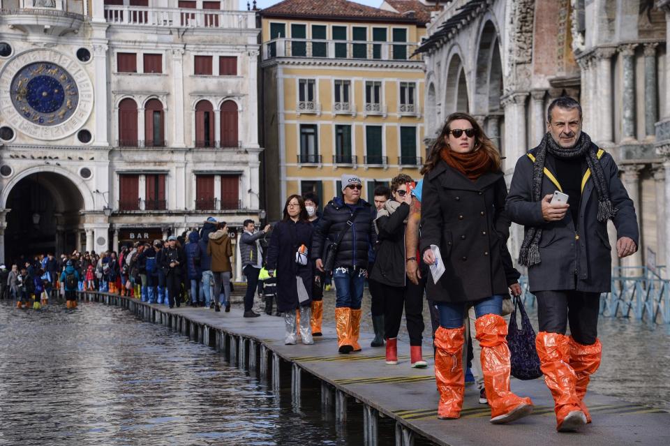 Tourists wearing waterproof gear in flooded Venice (AFP via Getty Images)