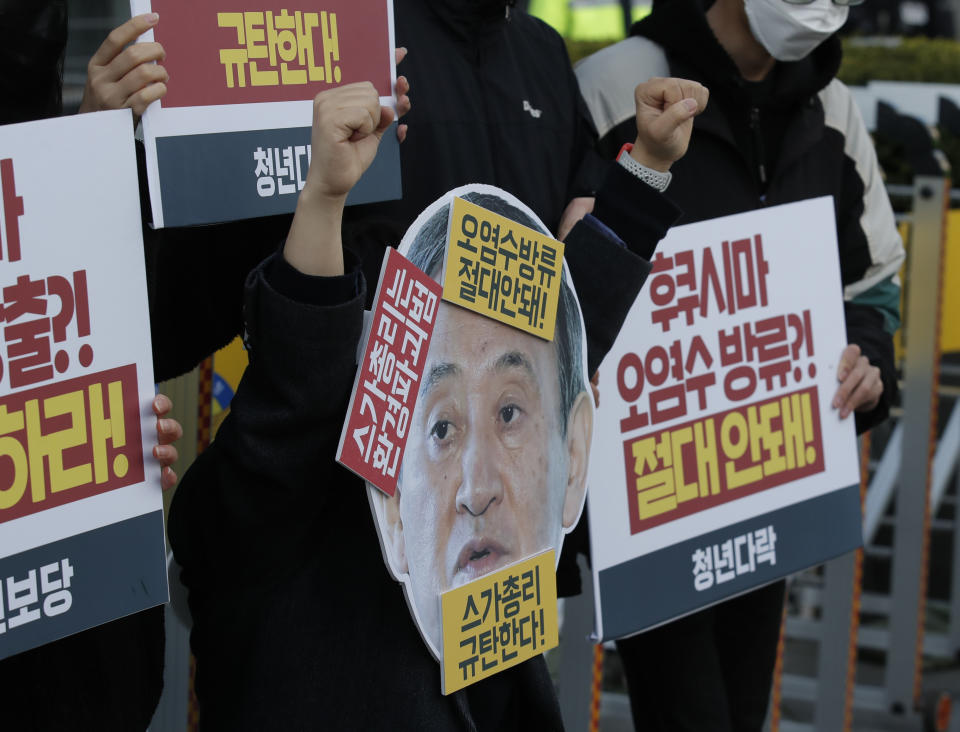 A member of youth groups wearing a cutout of Japanese Prime Minister Yoshihide Suga performs to denounce the Japan government's decision on Fukushima water, in Seoul, South Korea, Tuesday, April 13, 2021. Japan's government decided Tuesday to start releasing massive amounts of treated radioactive water from the wrecked Fukushima nuclear plant into the Pacific Ocean in two years - an option fiercely opposed by local fishermen and residents. The Korean letters read: "Denounce Prime Minister Yoshihide Suga." (AP Photo/Lee Jin-man)
