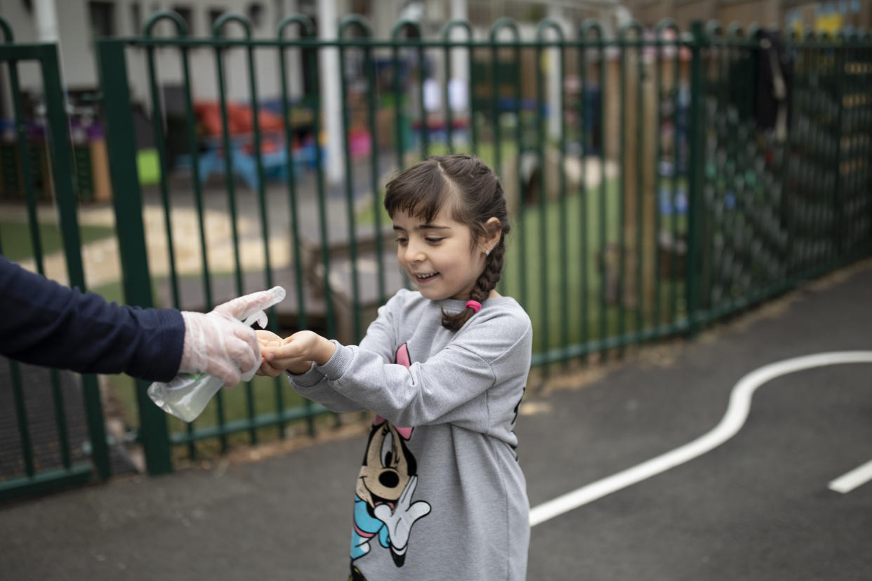 LONDON, ENGLAND - JUNE 04: A child is given hand sanitiser by a member of staff at the Harris Academy's Shortland's school on June 04, 2020 in London, England. As part of Covid-19 lockdown measures, Harris Academy schools have taught smaller pods of students, to help maintain social distancing measures. With restrictions now lifting and the Government encouraging schools to re-open, the school staff has been working to find the best way to provide extra spaces while still retaining the correct social distancing measures and cleanliness requirements. This week, some schools across England reopened for some students, with children in reception, Year 1 and Year 6 allowed to return first. (Photo by Dan Kitwood/Getty Images)