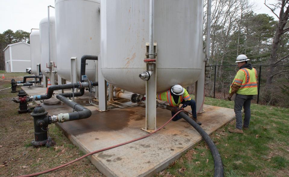 Hyannis Water Department's lead operator Davian Levy, left and Lyon Matocinos, prepare to open a valve under a treatment tank filled with activated charcoal used to treat groundwater for PFAS at a treatment plant off Mary Dunn Road in Hyannis. The tanks are periodically flushed out and filled with new charcoal.