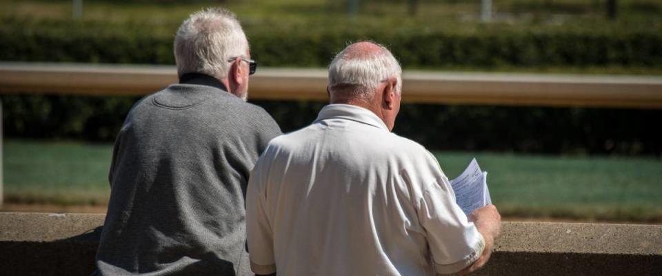 MEN AT HORSE TRACK WAITING FOR RACE TO START