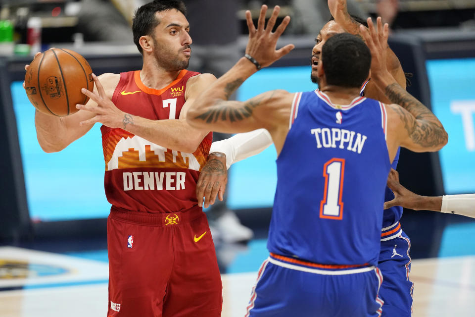 Denver Nuggets guard Facundo Campazzo, left, looks to pass the ball as New York Knicks forward Obi Toppin, front right, and guard Derrick Rose defend in the first half of an NBA basketball game Wednesday, May 5, 2021, in Denver. (AP Photo/David Zalubowski)