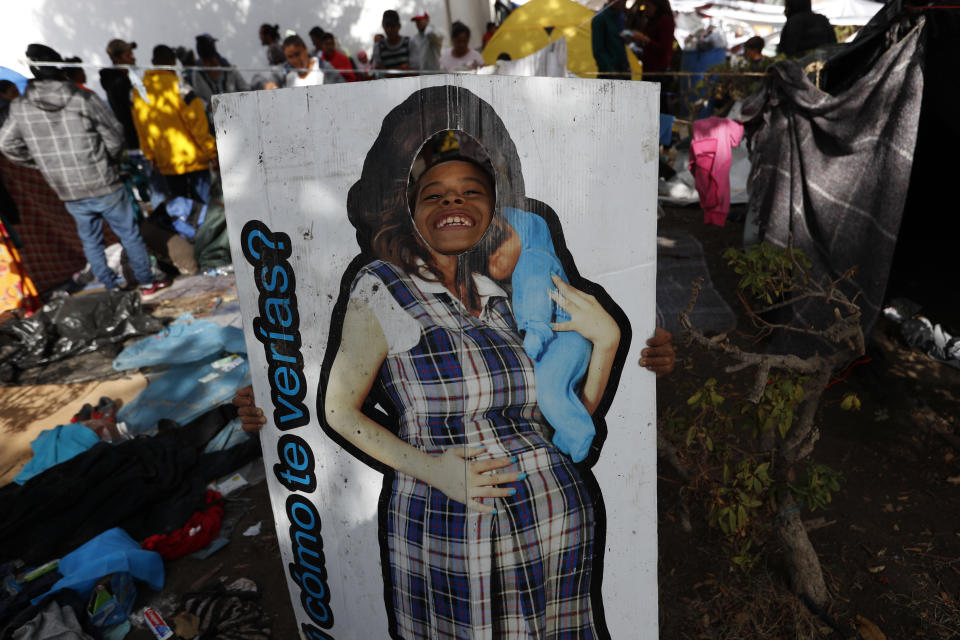 A boy plays with a life-size cardboard cutout of a pregnant woman at the Benito Juarez sports complex, in Tijuana, Mexico, on Friday, Nov. 30, 2018. Authorities in the Mexican city of Tijuana have been transferring the more than 6,000 Central American migrants from an overcrowded shelter on the border to an events hall further away. (AP Photo/Rebecca Blackwell)