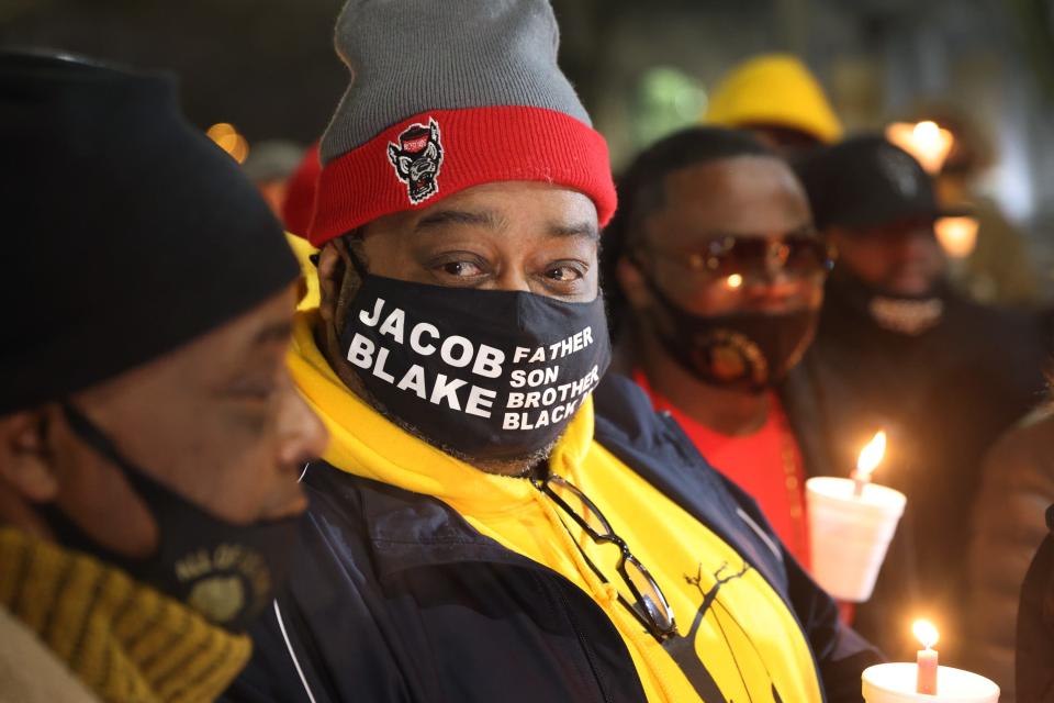 jacob blake sr wears a mask that says jacob blake father son brother black man holding a candle with justin blake at his side