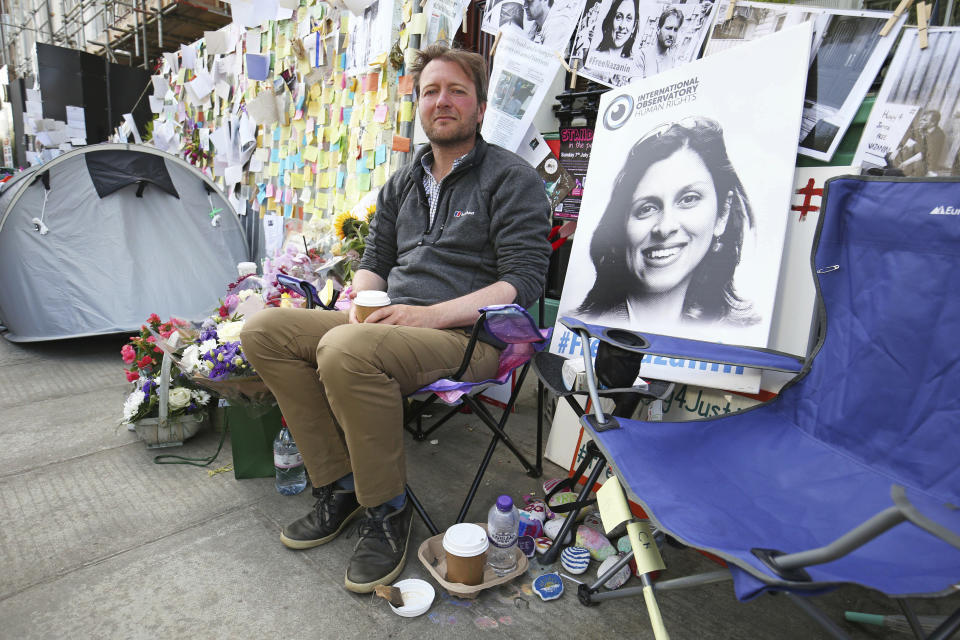 Richard Ratcliffe, the husband of detained Nazanin Zaghari Ratcliffe, seen in poster, outside the Iranian Embassy in London, Saturday June 29, 2019, on the day he ended his 15-day hunger strike and his imprisoned wife also ended her own hunger in an Iran jail.  Richard Ratcliffe has been camping outside the Iranian Embassing to support his wife Nazanin Zaghari-Ratcliffe, the British-Iranian woman convicted in 2016 and jailed for five years for alleged spying against Iran. (Jonathan Brady/PA via AP)