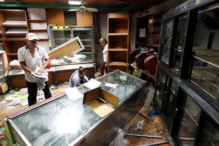 Workers look for valuables among the damaged goods in a bakery after it was looted in Caracas, Venezuela April 20, 2017. REUTERS/Christian Veron