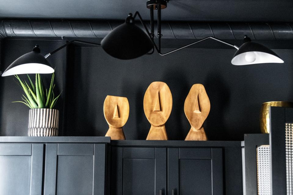 African wood sculptures rest on top of kitchen cabinets.