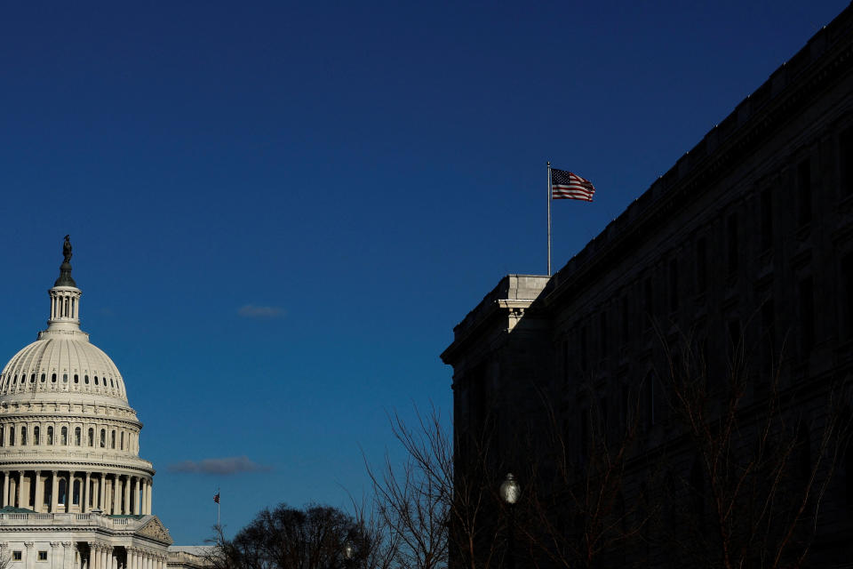 The U.S. flag flies over the Cannon House Office Building on Capitol Hill. The Capitol can be seen to the left.