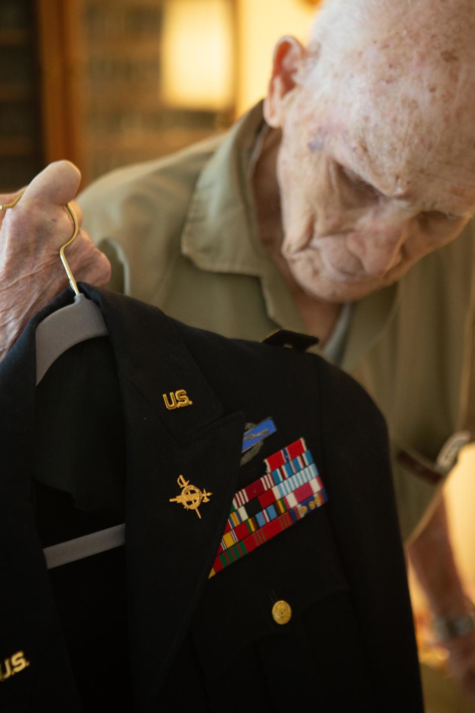 Holding up his retired uniform, Crosby "Bing" Powell, 96, talks about his time serving in the U.S. Army during World War II. The current owner of Powell's former home, Mikell Burr, found some of Powell's war medals and memorabilia in the loft above her garage when she was cleaning it out over the Labor Day weekend.