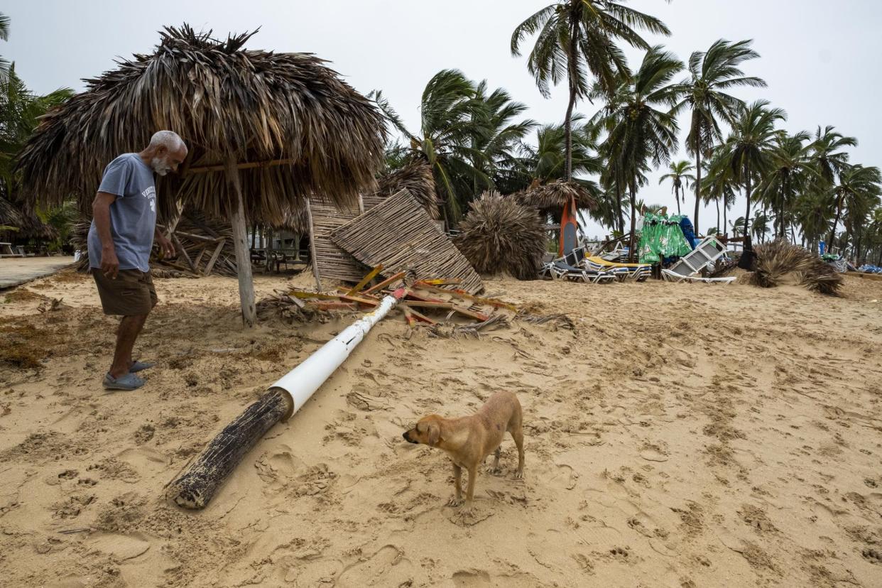 A vendor works amid the debris of his small business of umbrella rentals and food after they were felled by Hurricane Fiona on the beach in Punta Cana, Dominican Republic, Monday, Sept. 19, 2022.