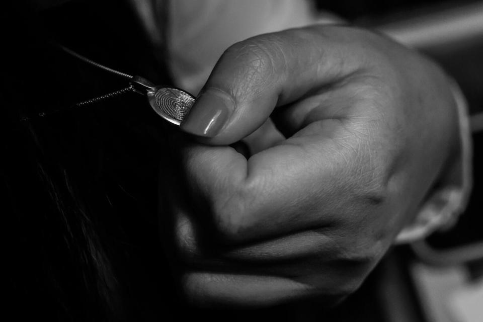 A hand holds a pendant.