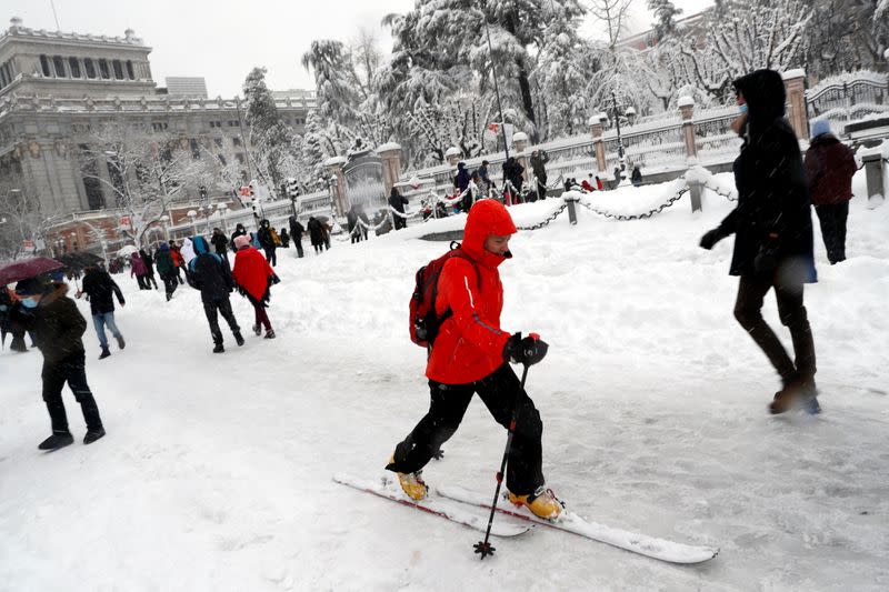 People walk and ski downtown during a heavy snowfall in Madrid