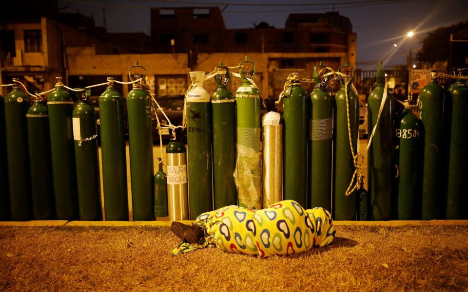 A person sleeps next to empty oxygen tanks to save a spot in the queue, as the supplier refills a tank per person and attends only up to 60 people a day in Callao, Peru -  REUTERS/Sebastian Castaneda