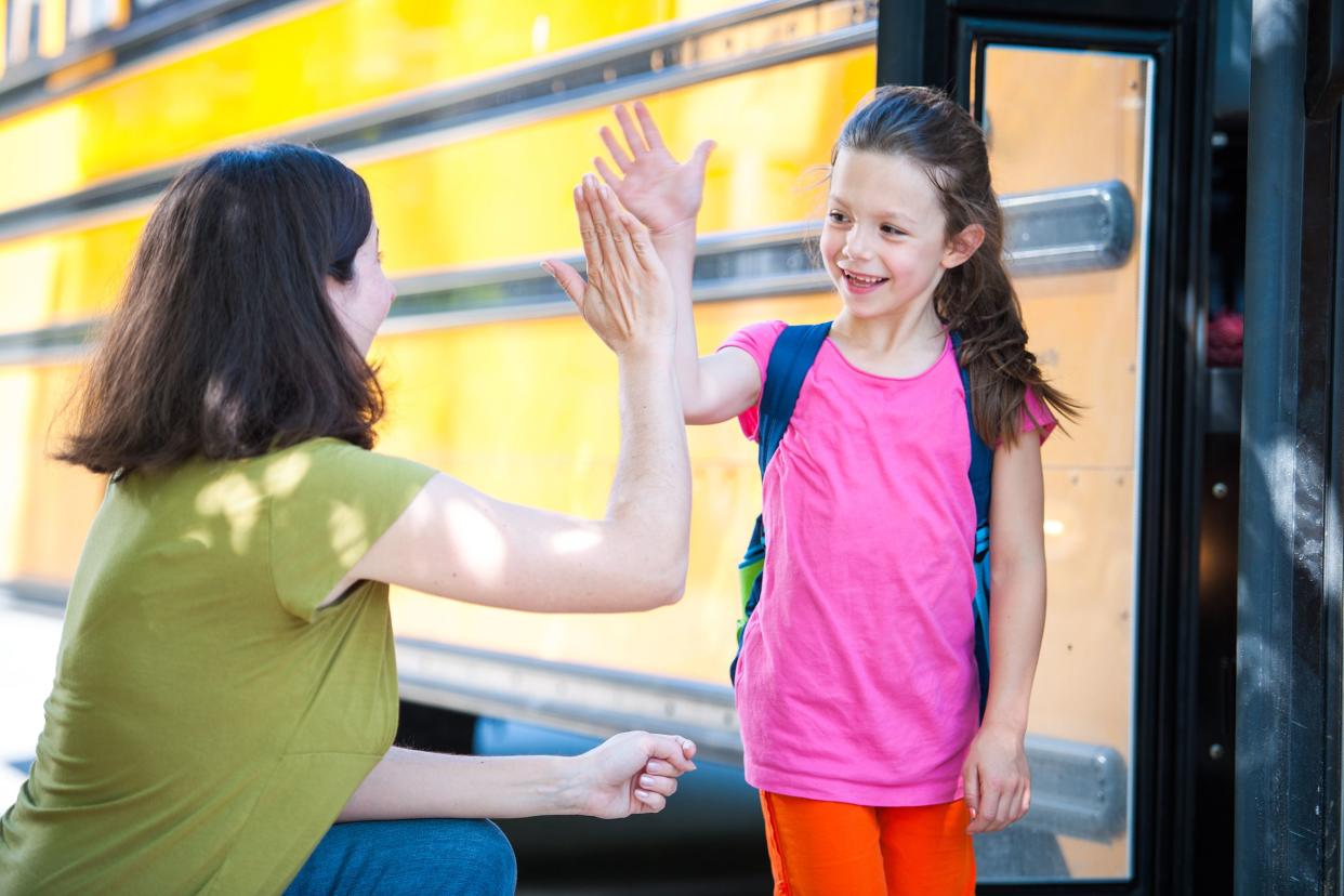 Mom giving her daughter a high-five before getting on the school bus