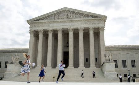 Interns with media organizations run with the decision upholding the Affordable Care Act at the Supreme Court in Washington June 25, 2015. REUTERS/Joshua Roberts