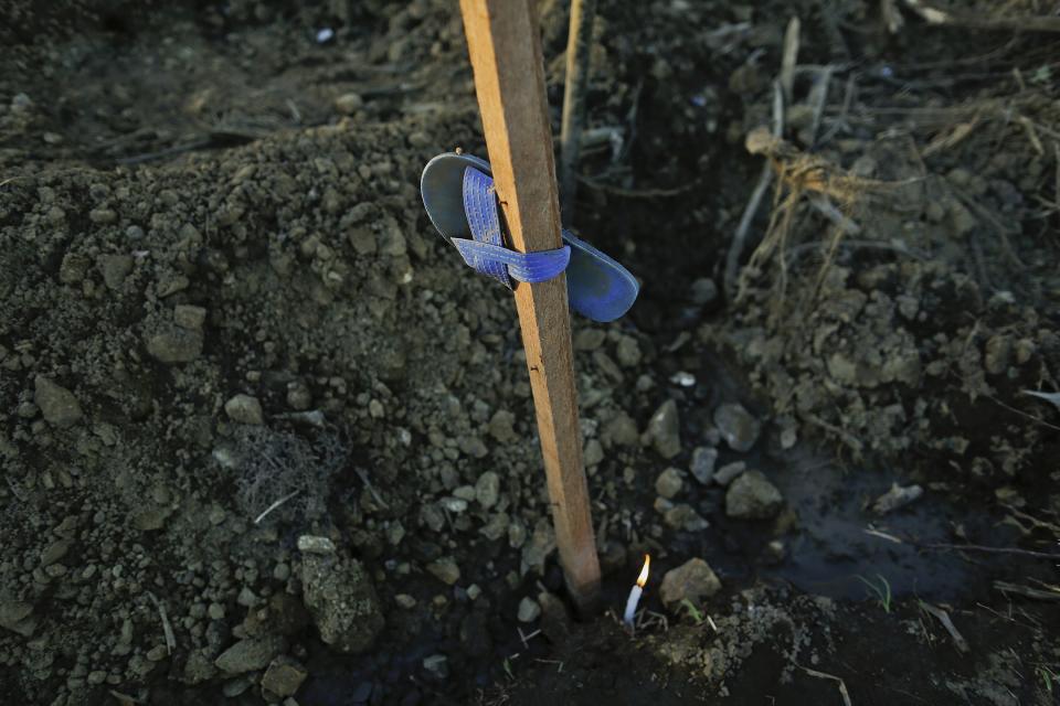 A candle lit by Marilou Cassanares is left by a mass grave where her husband was buried in Palo