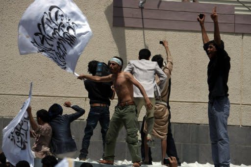 A Yemeni protester waves a flag outside the gate of the US embassy in Sanaa. The US boosted security at its embassies amid fears that more anti-American violence sparked by a film mocking Islam could erupt after Friday's Muslim prayers across the Middle East and North Africa