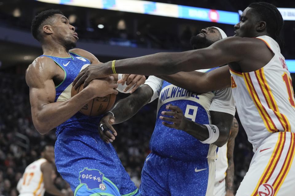 Milwaukee Bucks' Cameron Payne grabs a rebound in front of Atlanta Hawks' Clint Capela during the first half of an NBA basketball game Saturday, Dec. 2, 2023, in Milwaukee. (AP Photo/Morry Gash)