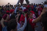 Aficionados de la selección de Túnez se sacan fotos frente al reloj con la cuenta regresiva del Mundial de Qatar 2022, en Doha, el viernes 21 de octubre de 2022. (AP Foto/Nariman El-Mofty)