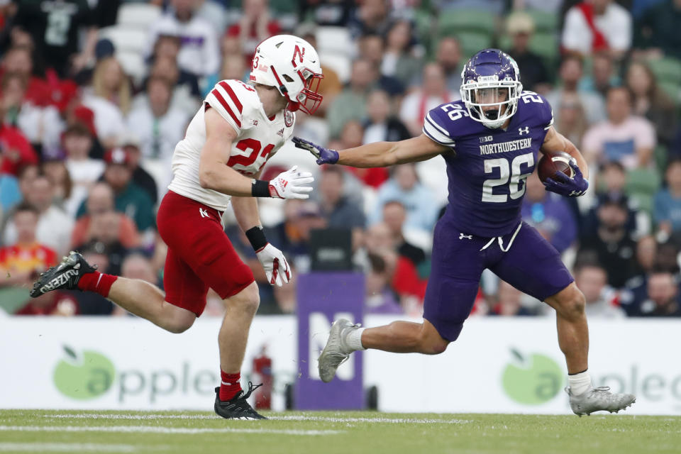 Northwestern running back Evan Hull (26) runs from Nebraska defender Isaac Gifford, left, during the second half of an NCAA college football game, Saturday, Aug. 27, 2022, at Aviva Stadium in Dublin, Ireland. (AP Photo/Peter Morrison)