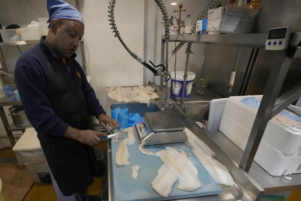 A man prepares fish at Olley's Fish Experience shop in London, Wednesday, Sept. 28, 2022. Like many small business owners in Britain, Harry Niazi hoped for government help to keep his south London fish and chip shop going in the face of rocketing energy bills and soaring inflation. But an economic stimulus plan announced last week by Prime Minister Liz Truss’ new government brought no relief — far from it. (AP Photo/Frank Augstein)