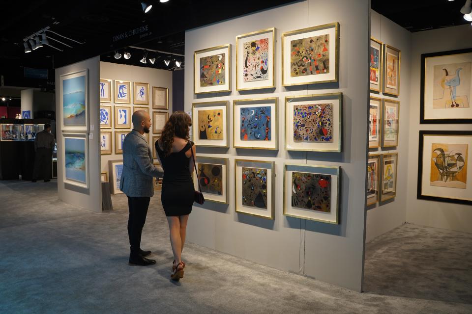 Patrons look over art in the Dinan and Chighine booth at the 2022 Palm Beach Show.