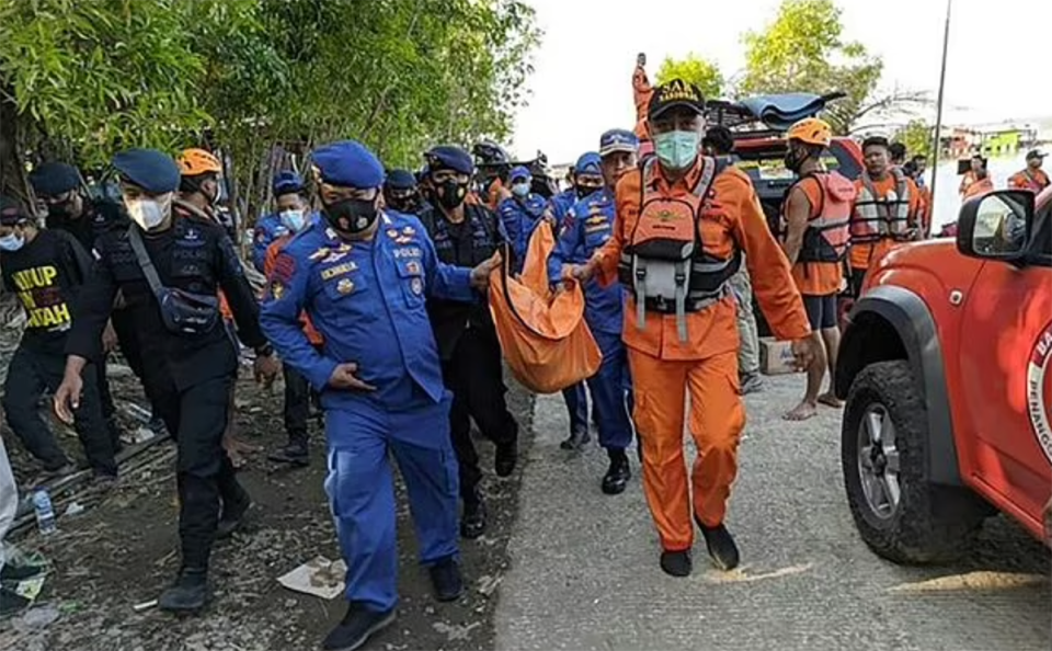 Rescuers carry a large bag away from the scene.