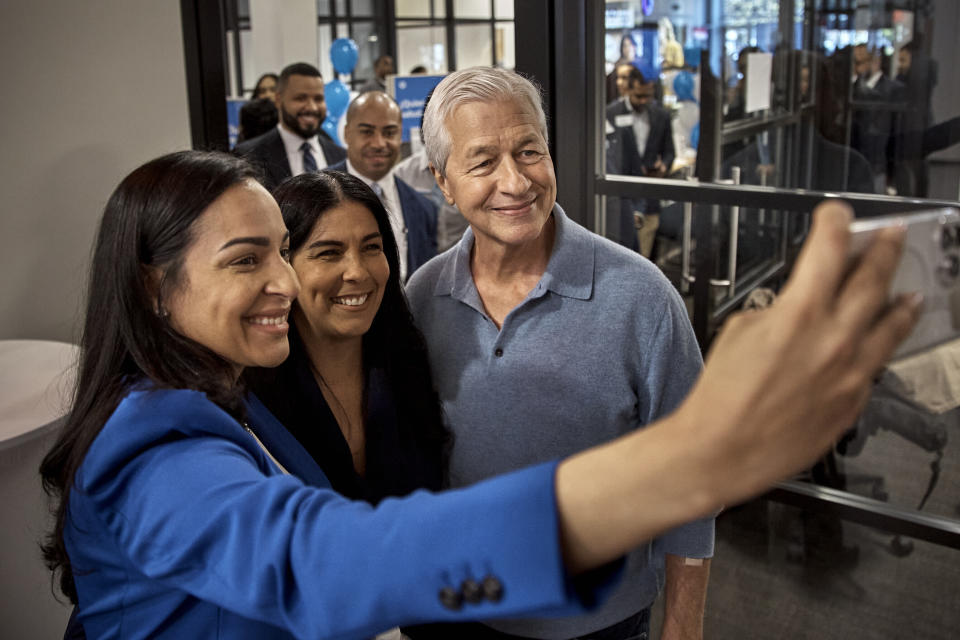 FILE - Jamie Dimon, CEO and chairman of JPMorgan Chase, center right, poses for a selfie with employees during the community branch opening in the Bronx borough of New York, on April 26, 2024. The nation's largest banks are spending hundreds of millions of dollars on refurbishing old locations or building new ones, and in the process changing the look, feel and purpose of the local bank branch. (AP Photo/Andres Kudacki, File)