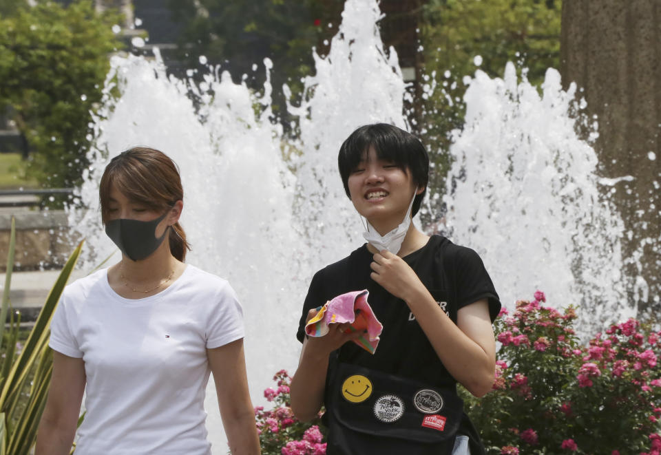 People wearing face masks to protect against the spread of the new coronavirus walk at park in Yokohama near Tokyo, Monday, Aug, 10, 2020. (AP Photo/Koji Sasahara)